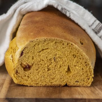 A side view of a loaf of pumpkin cranberry yeast bread.