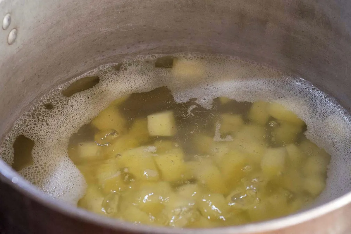 Potato cubes being simmered in a pot of water.