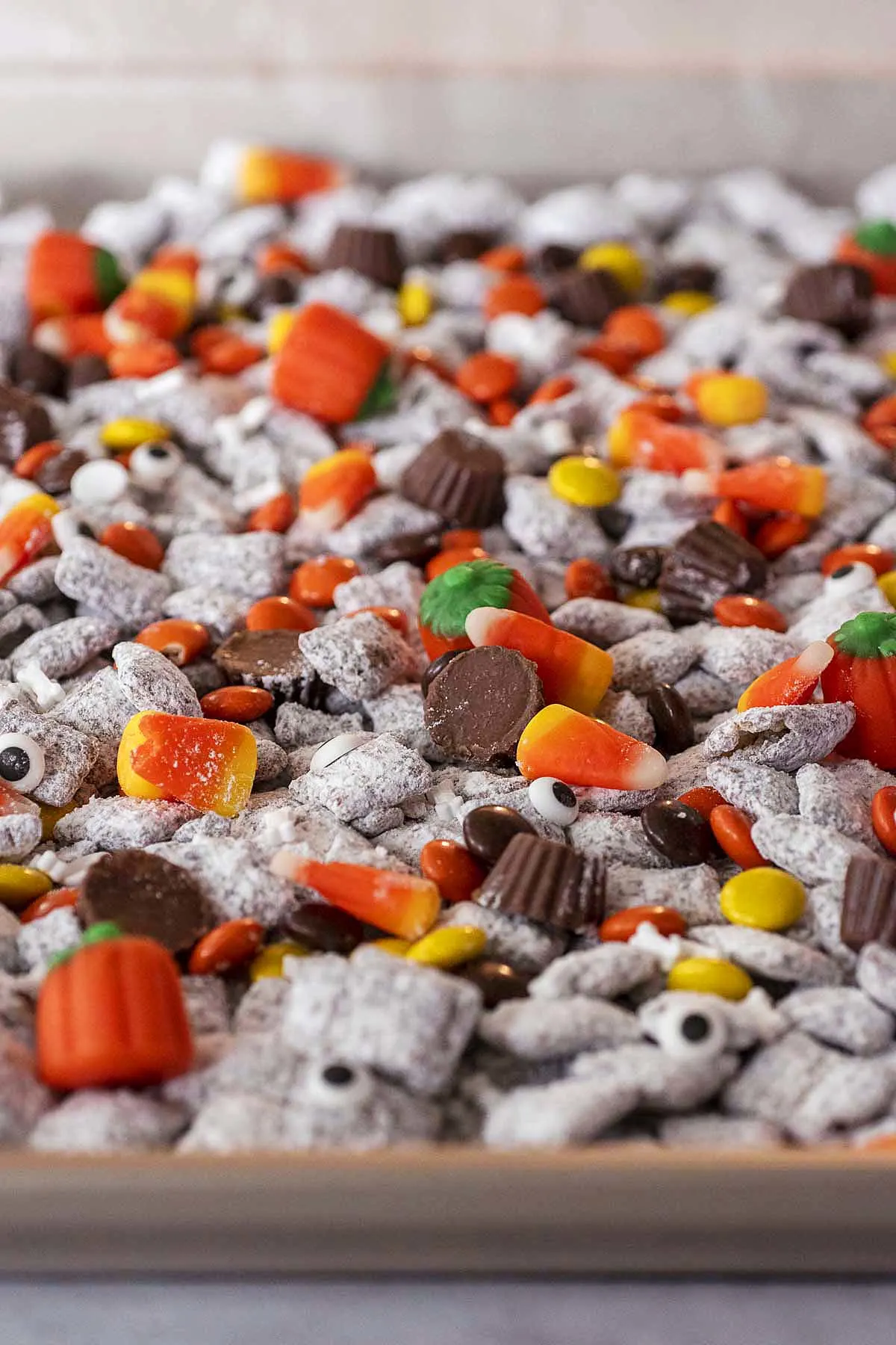 Halloween muddy buddies spread out on a cookie sheet.