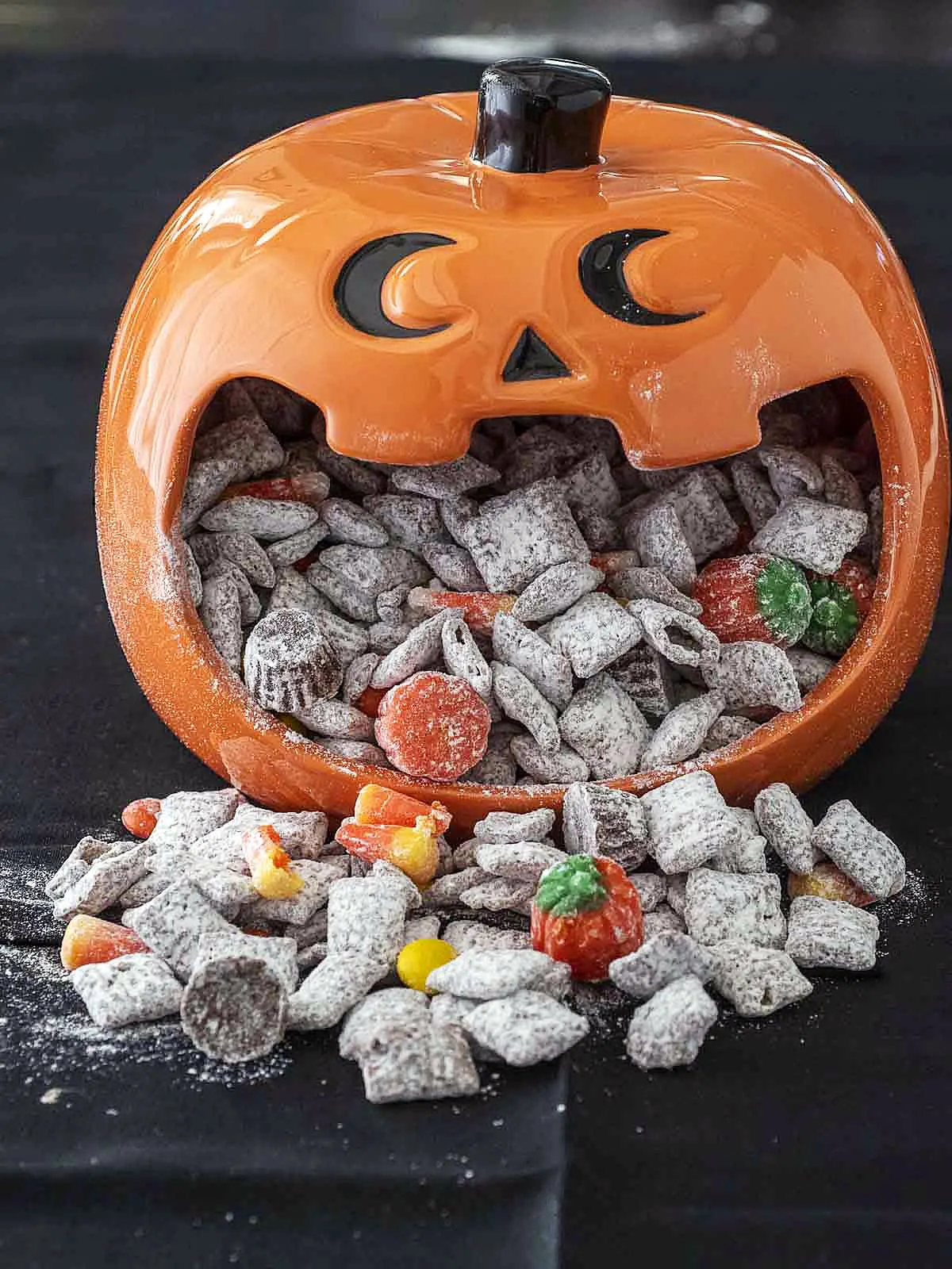 A jack-o-lantern candy dish full of Halloween Muddy Buddies.