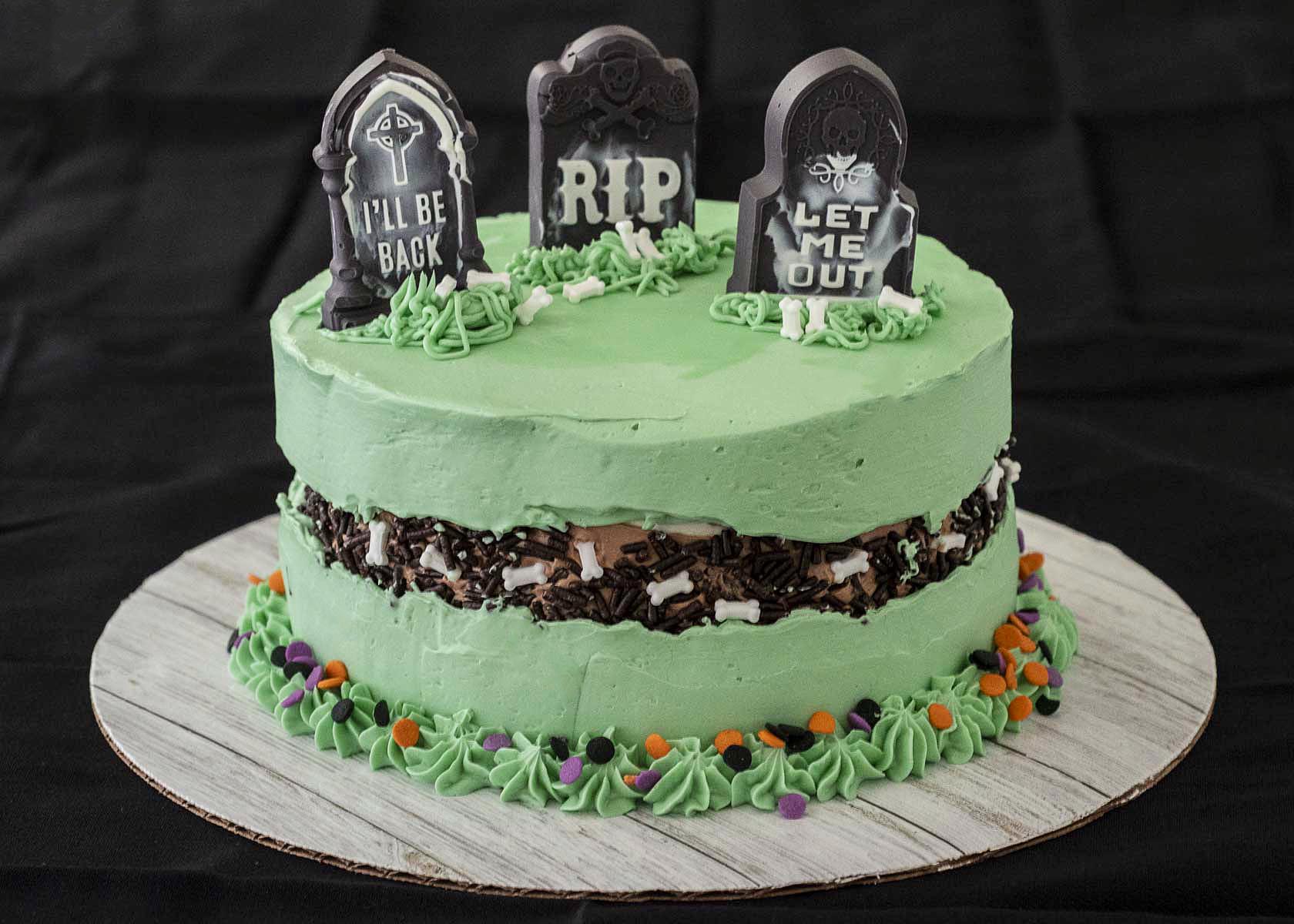 A fully decorated graveyard fault line cake on a black tablecloth.