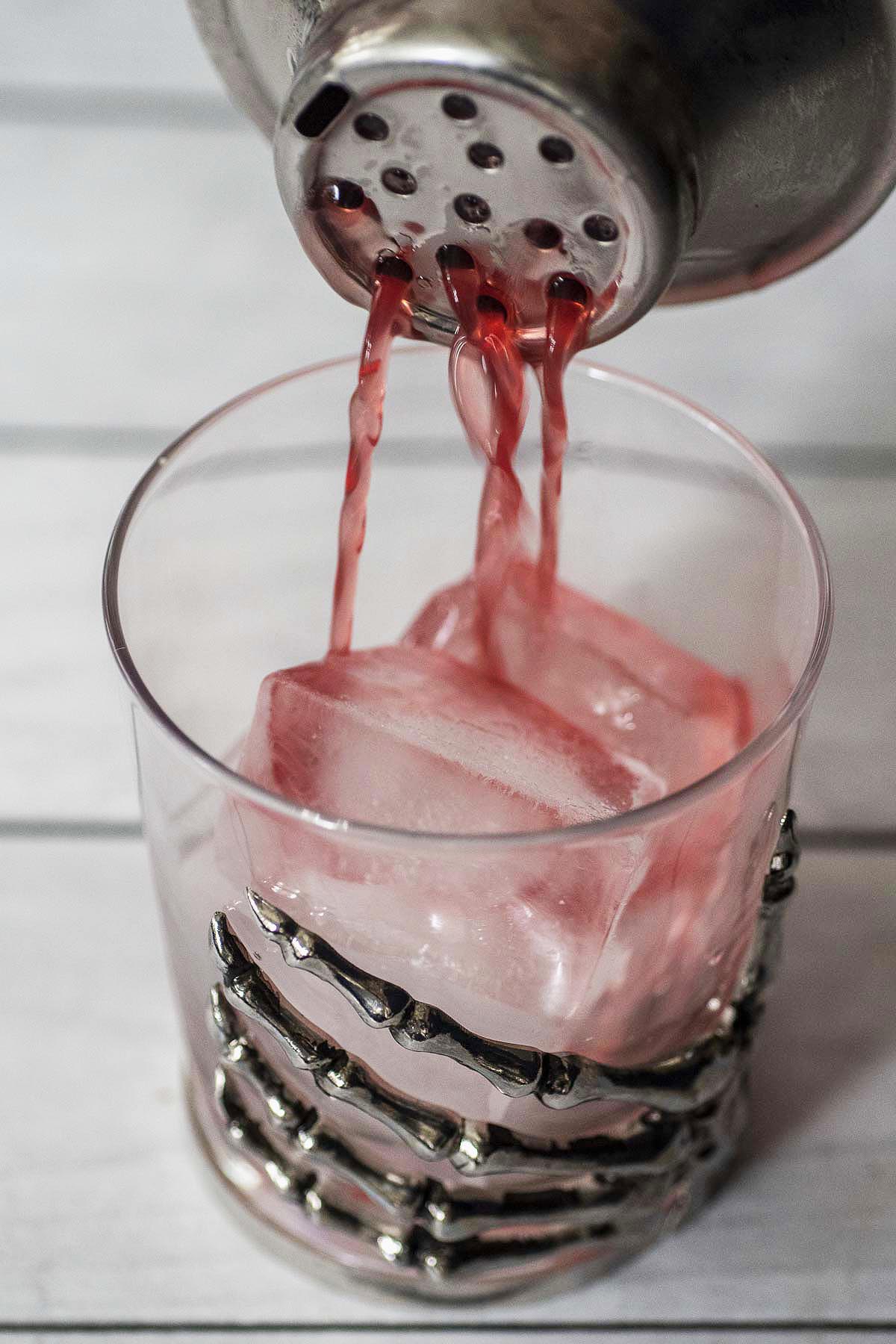 Witches' brew cocktail being poured into an old-fashioned glass. 