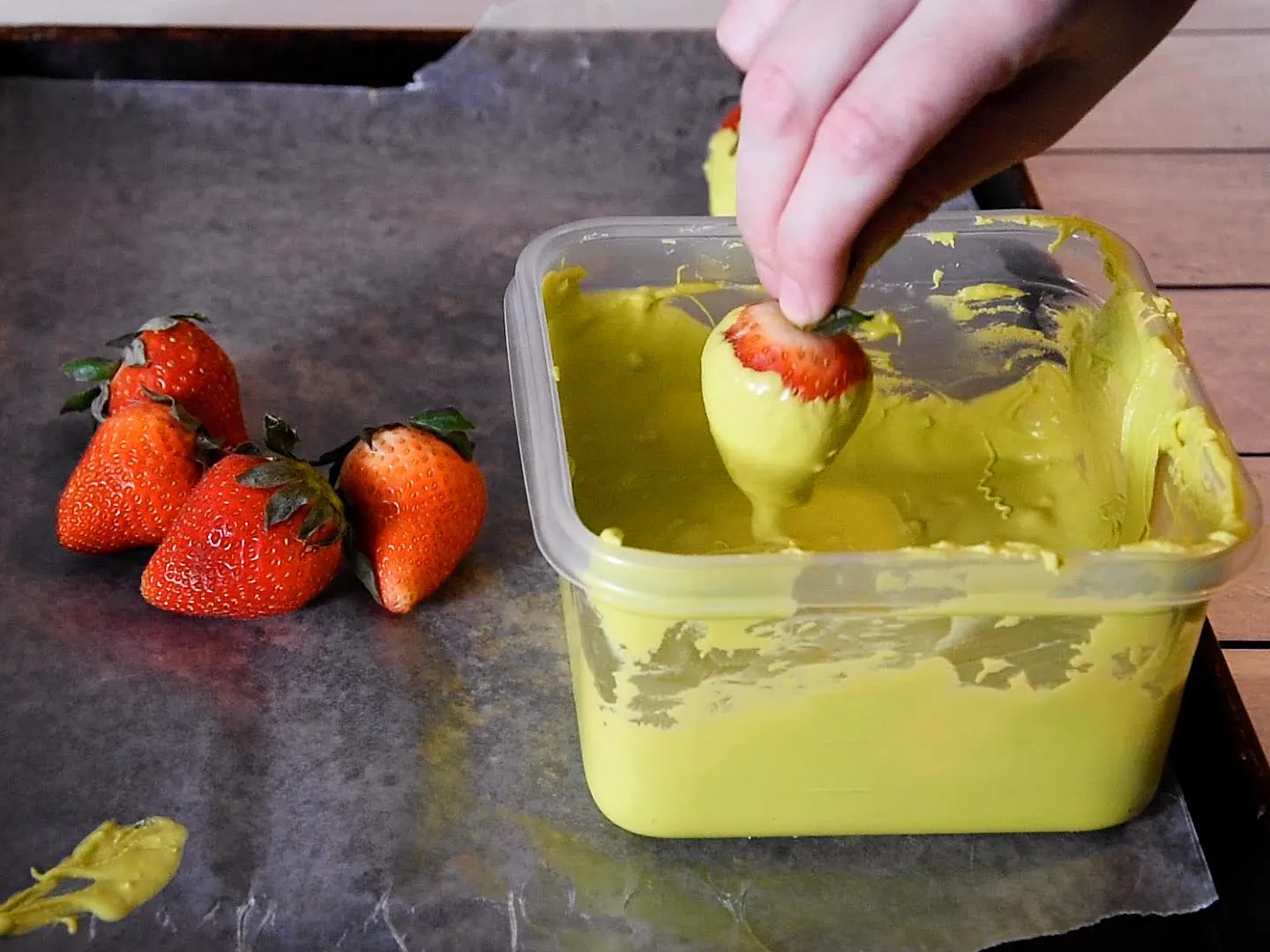 Strawberry Witches Step 1: dipping the strawberry in green candy coating.