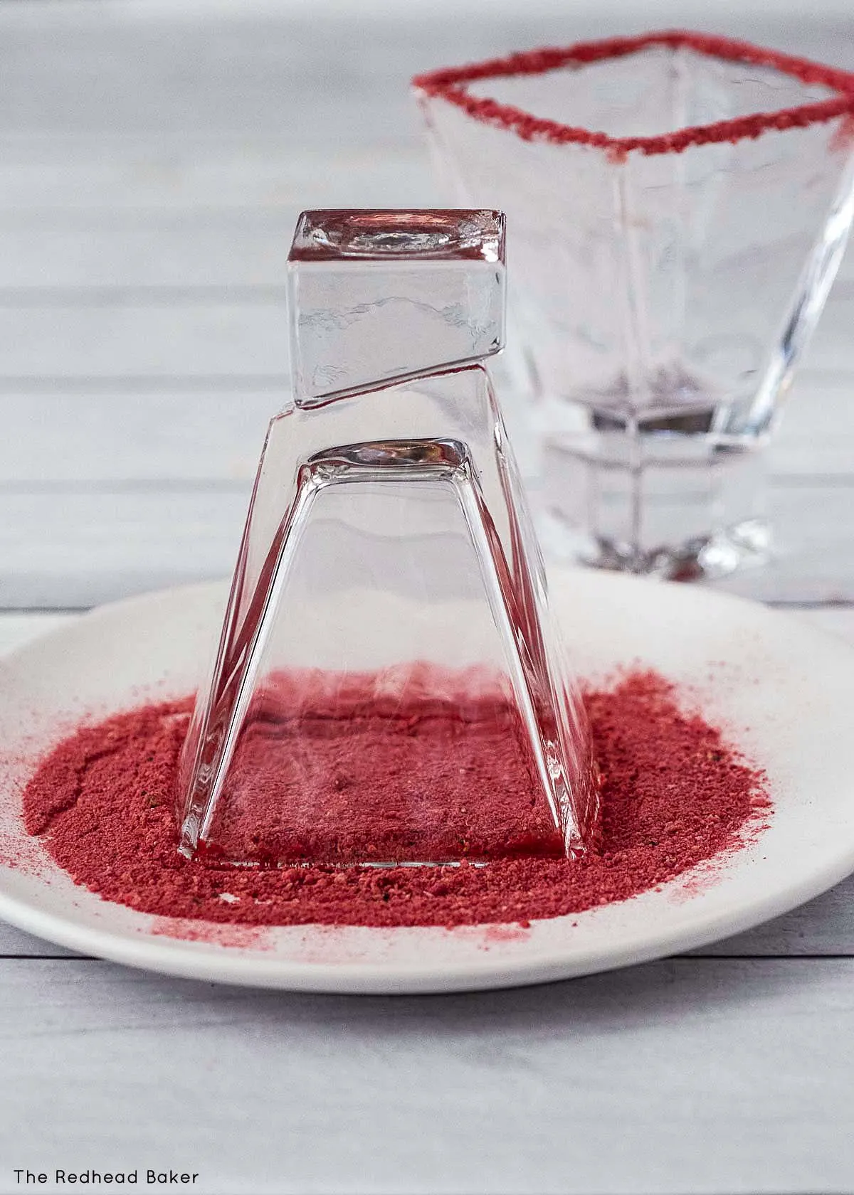 A martini glass sitting in a plate of powdered freeze-dried strawberries.