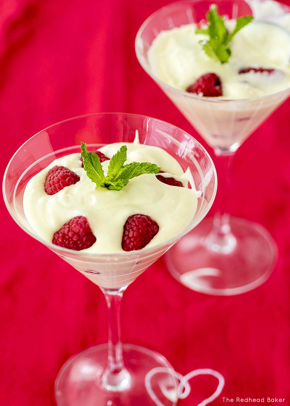 Two glasses of white chocolate mousse on a red cloth.