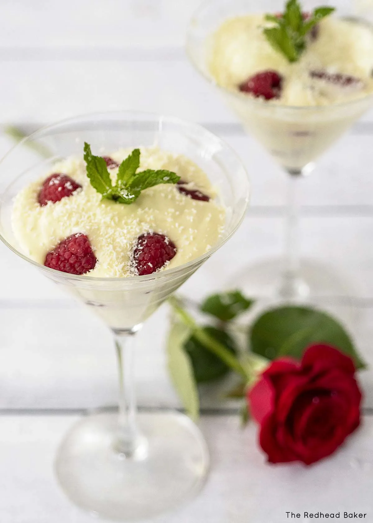 Two martini glasses of mousse garnished with mint.