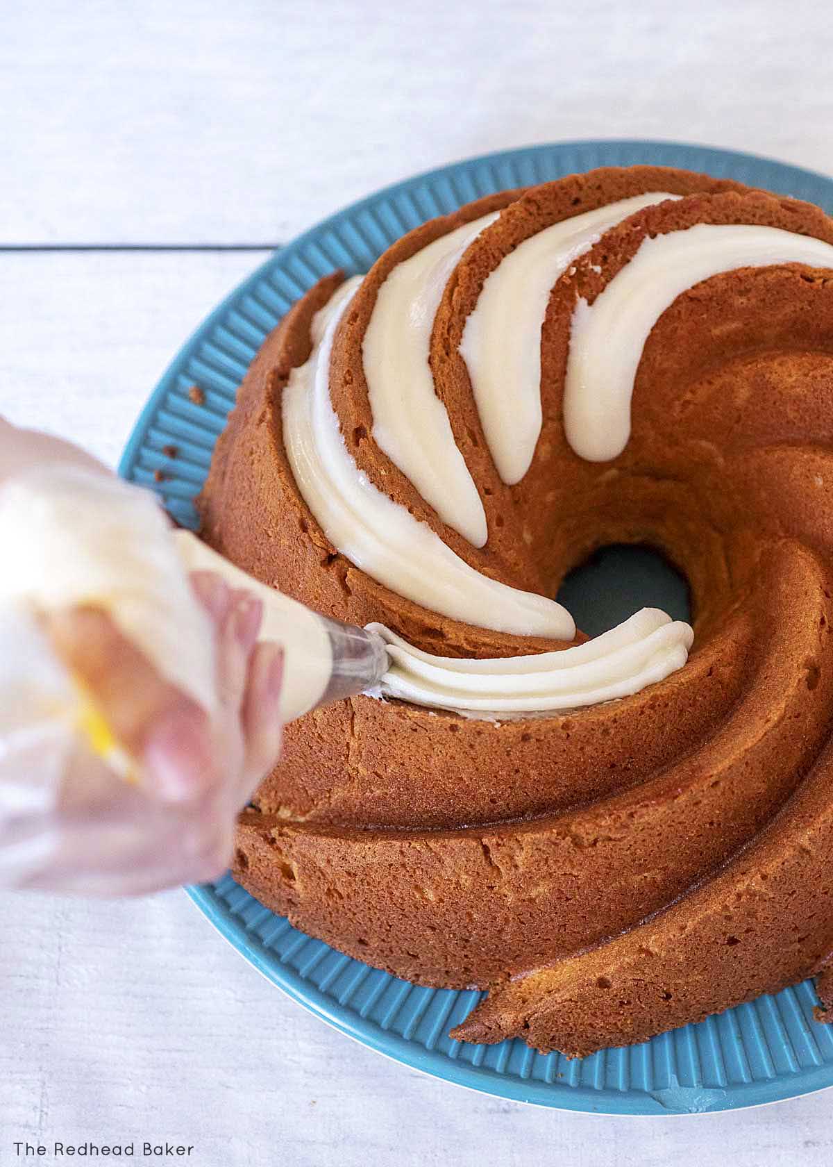 Piping frosting into the grooves of the bundt cake.