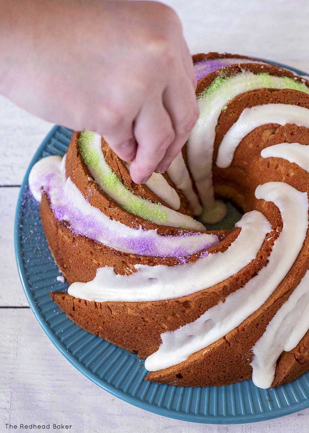 Sprinkling sugar onto the frosting of the cake.