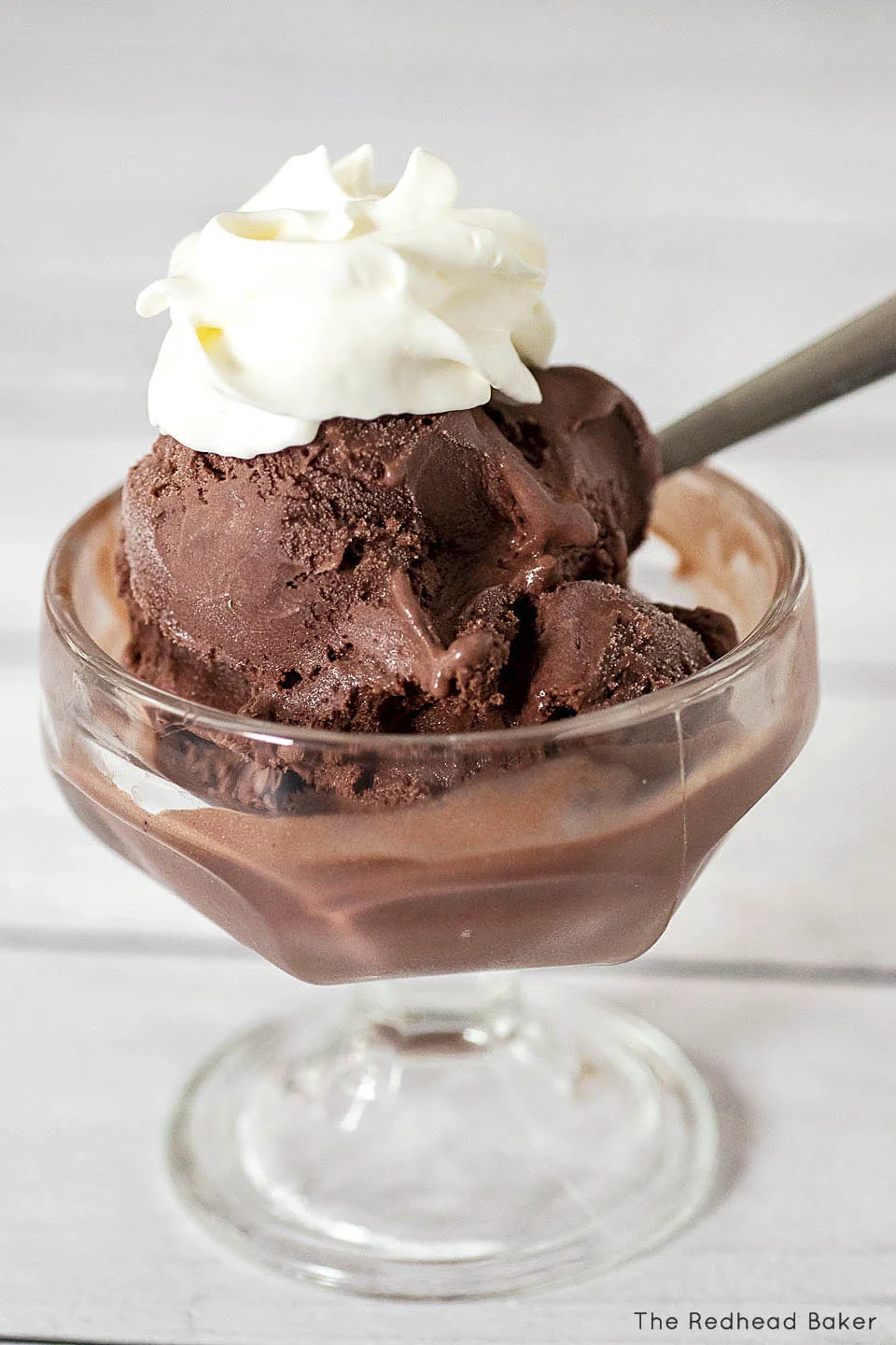 A glass dish of chocolate ice cream topped with whipped cream.