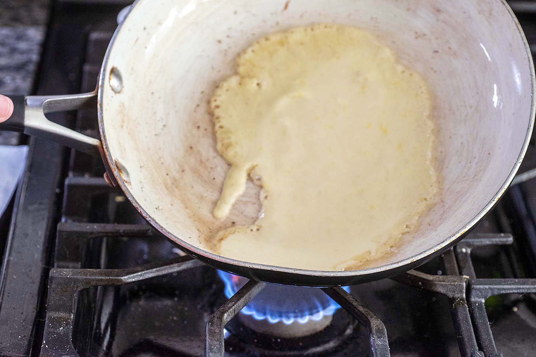 Tilting the skillet to coat with crepe batter.