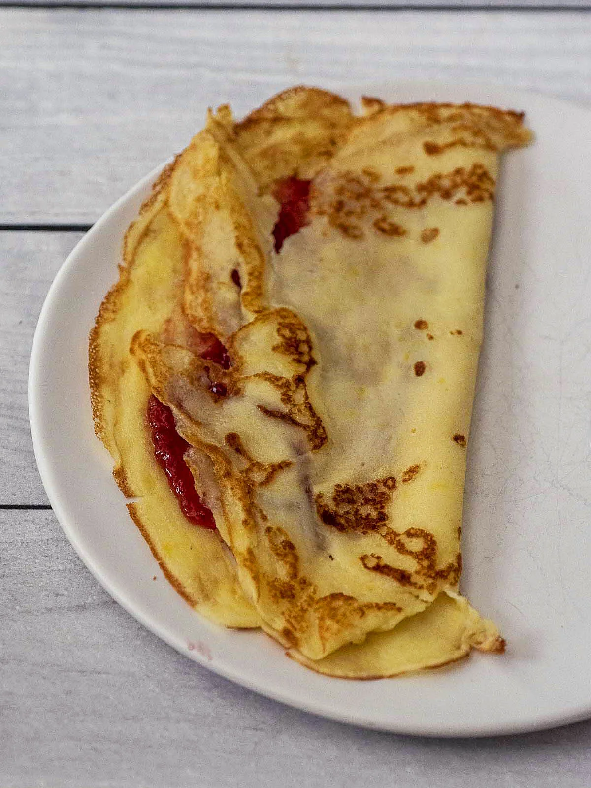A crepe filled with raspberry jam, folded in half. 