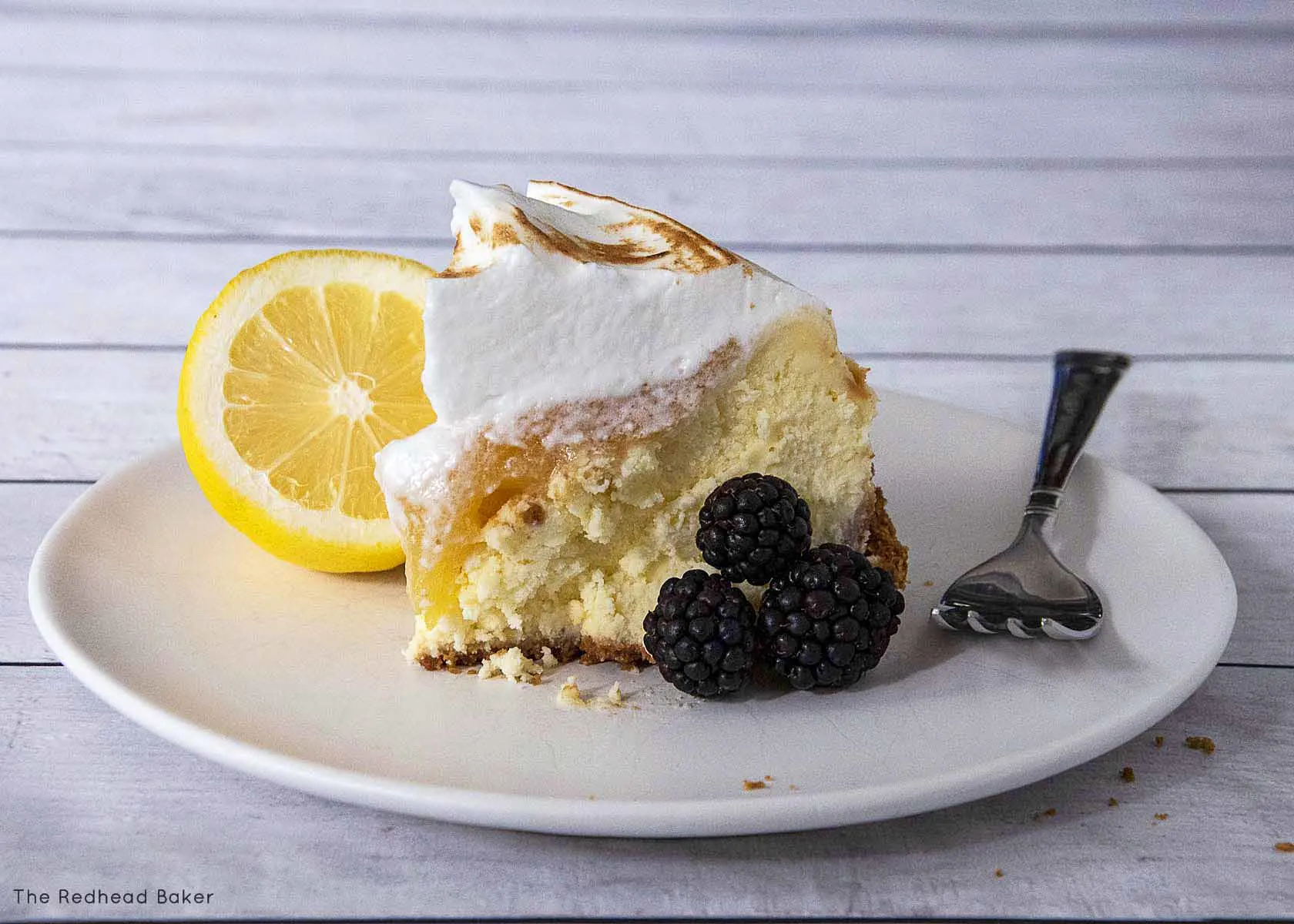 A slice of lemon meringue cheesecake with berries.