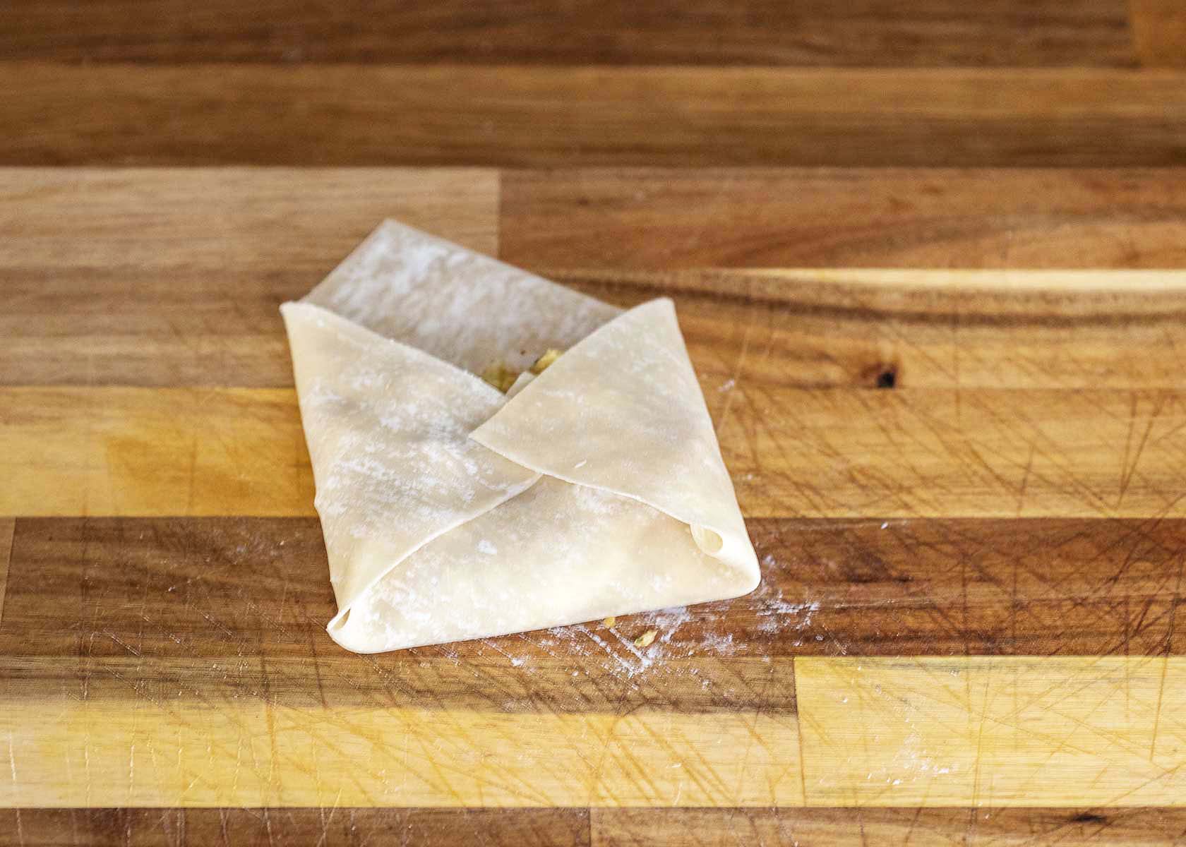 Folding in the left and right corners of the egg roll wrapper.