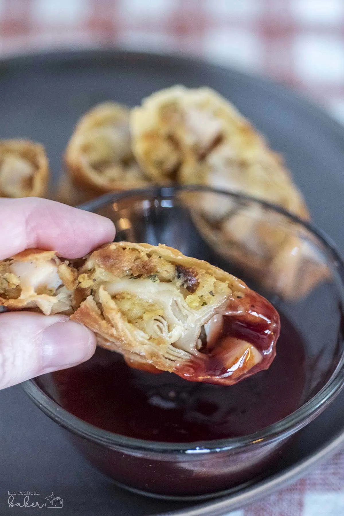 Half an egg roll dipped in cranberry sweet and sour sauce.