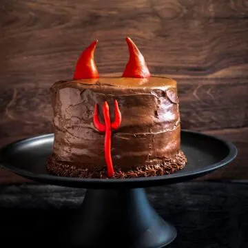 A devils food cake on a black cake stand.