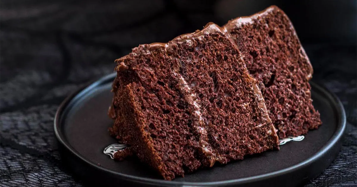 A slice of devils food cake on a black plate.