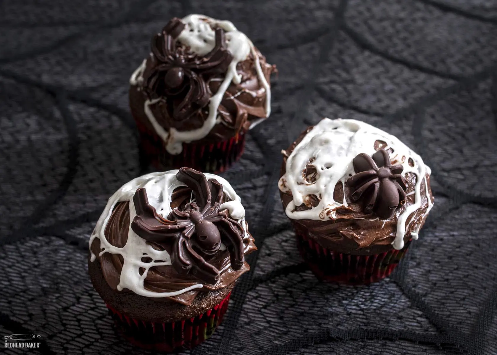 Three marshmallow spiderweb cupcakes.