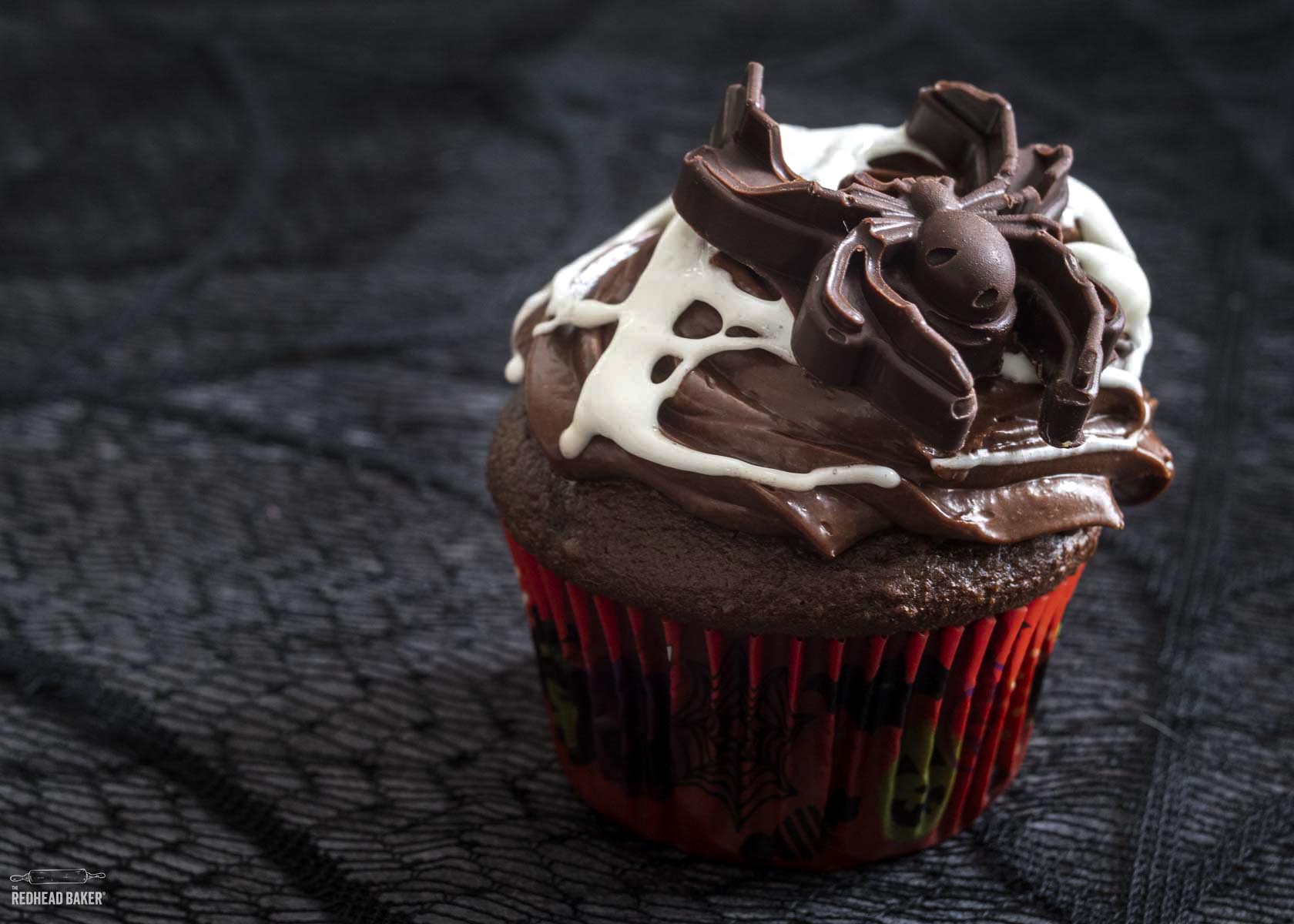 A single chocolate cupcake with marshmallow web and a large candy spider.