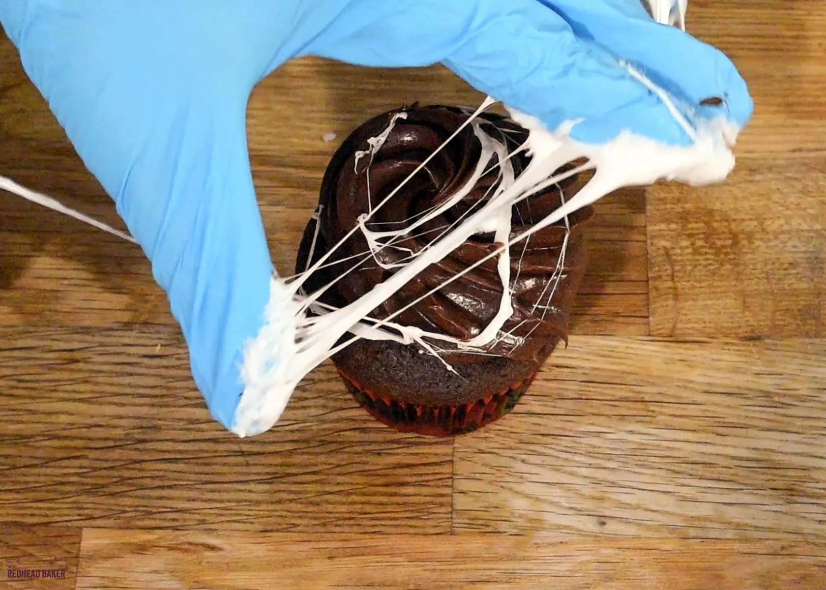 Stretching marshmallow web around a cupcake.