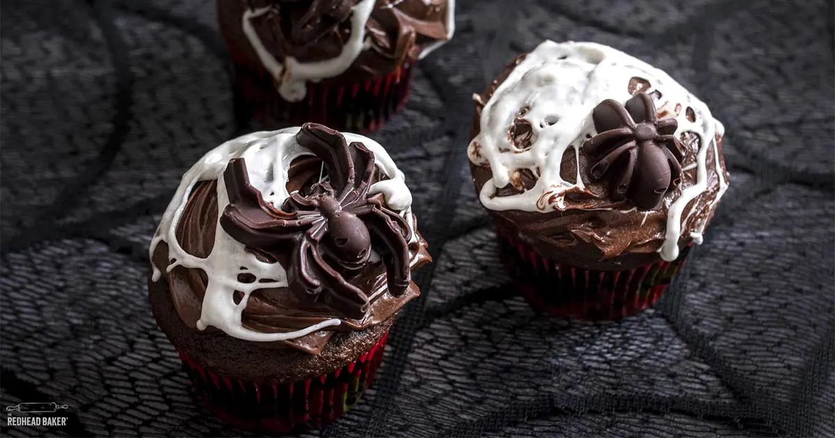Three marshmallow spiderweb cupcakes with candy spiders.
