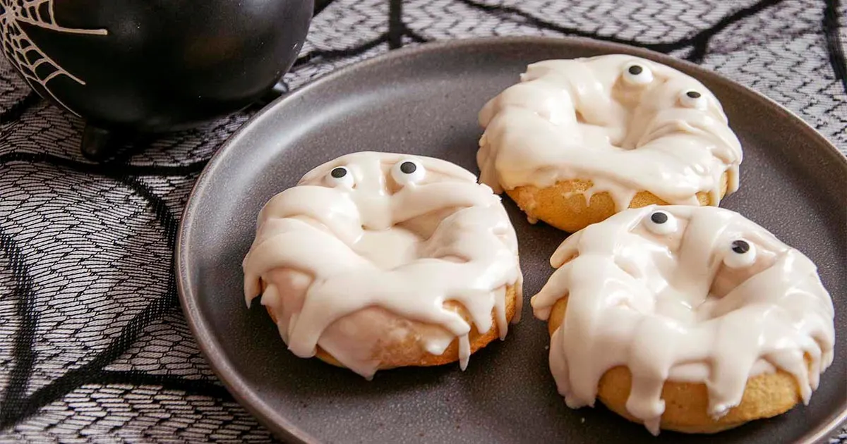 Three mummy donuts on a black plate.