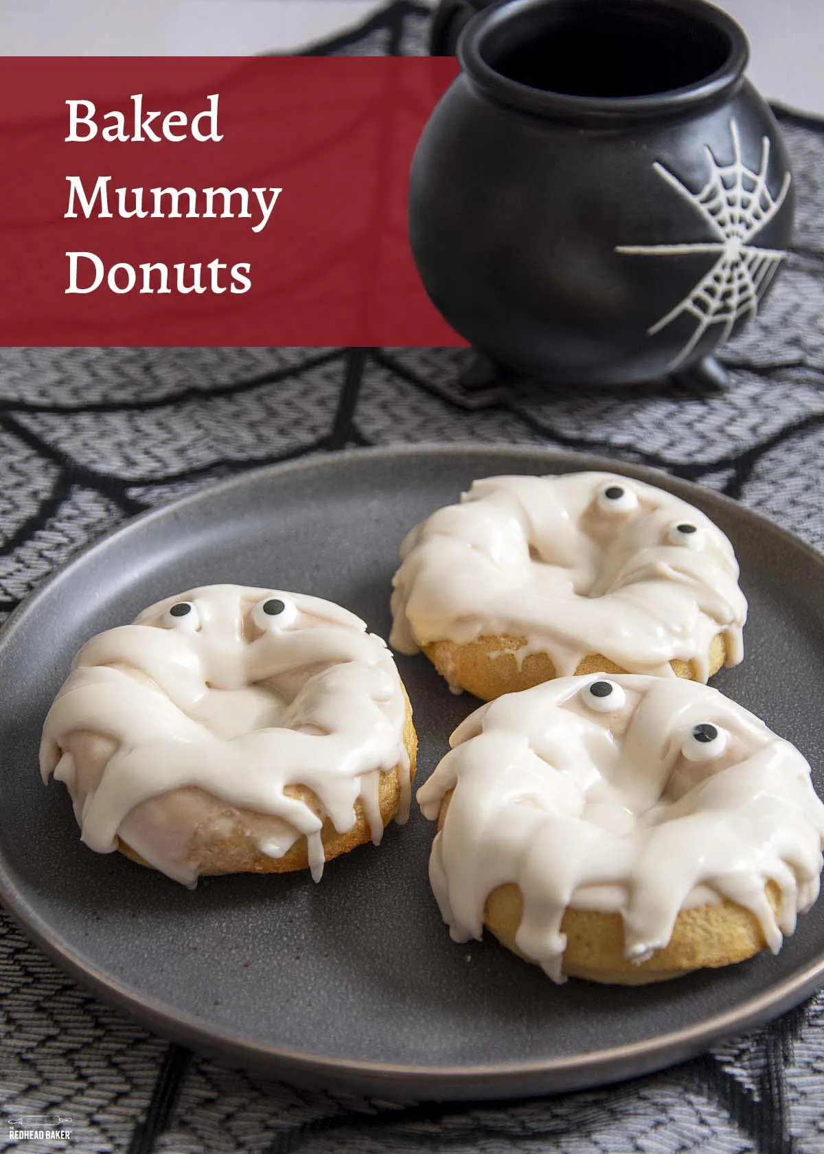Three mummy donuts on a black plate.