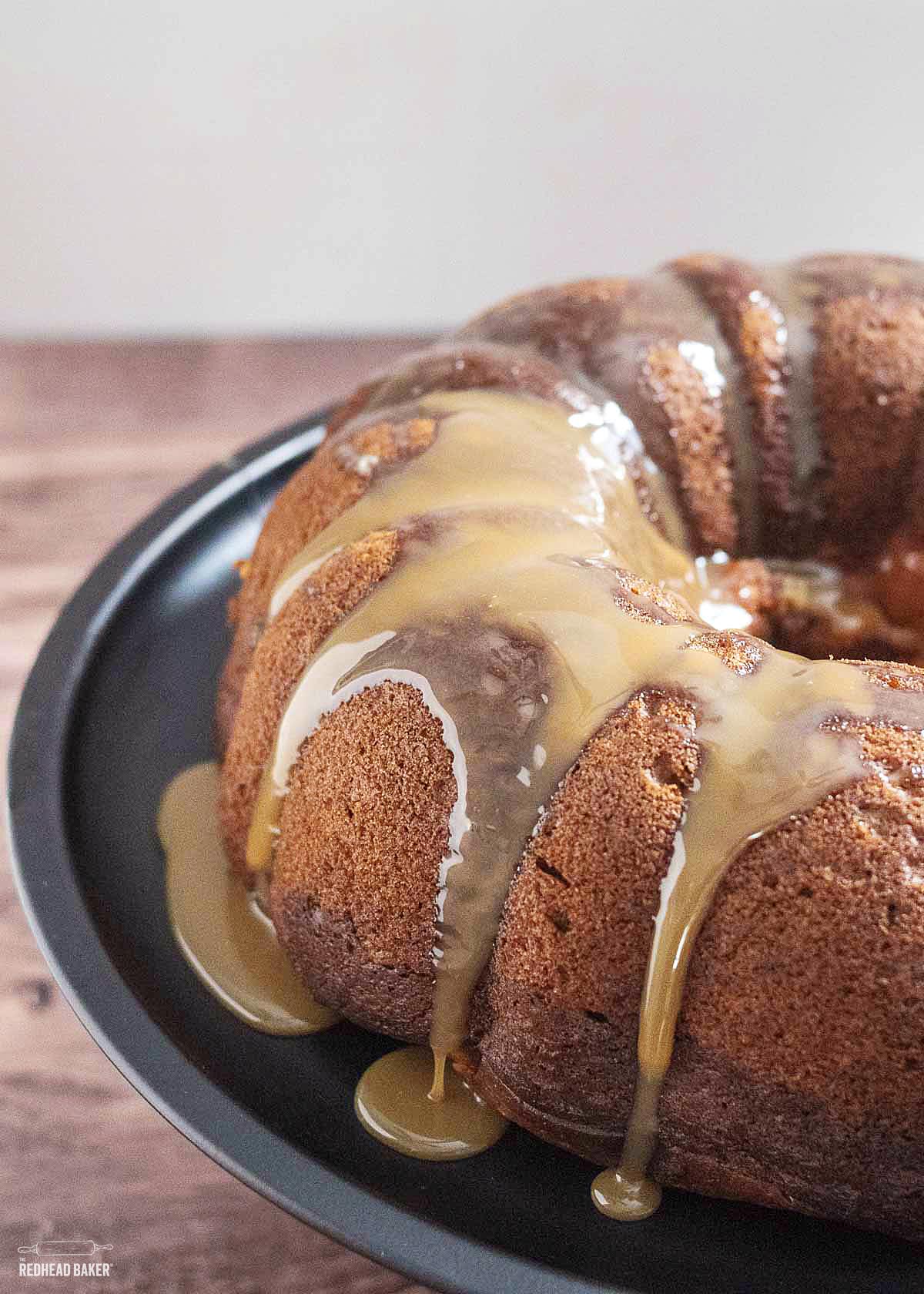 A pumpkin bundt cake on a black cake stand. 