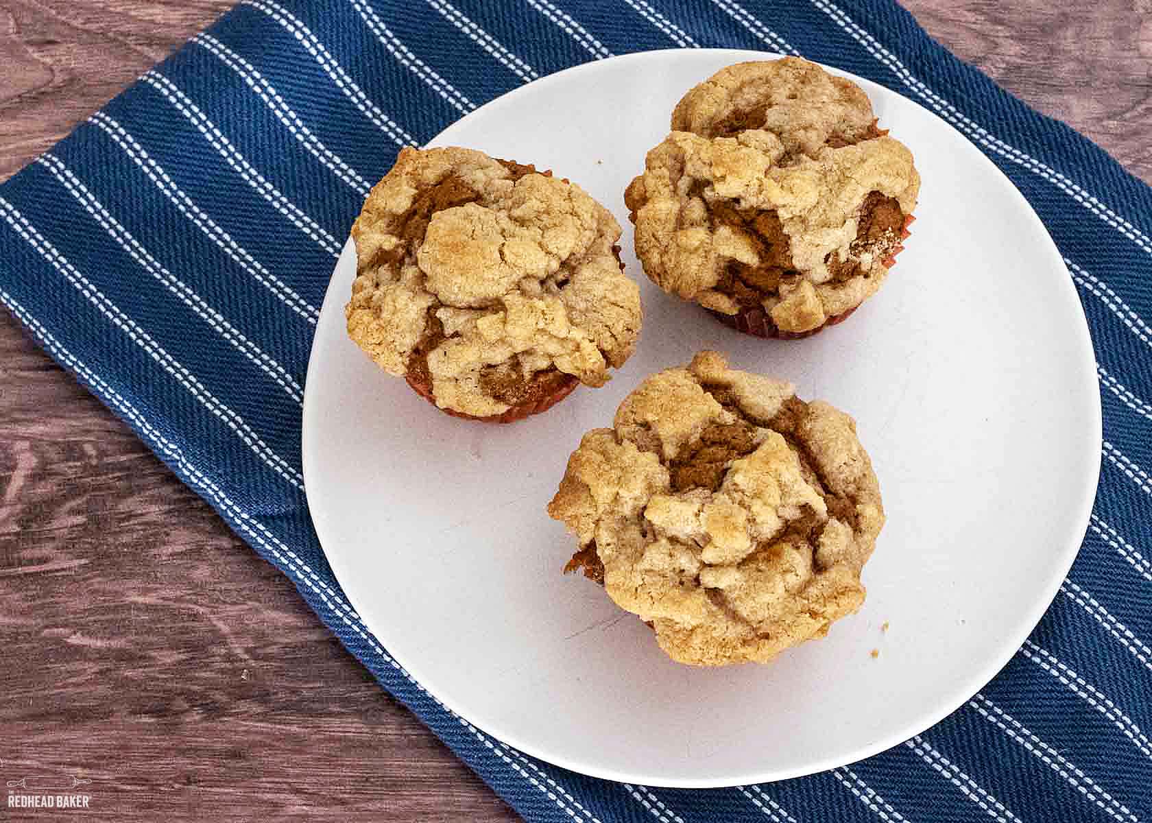 An overhead view of three pumpkin muffins on a white plate.