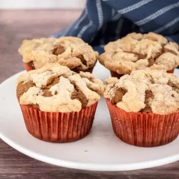 Four pumpkin muffins on a white plate.