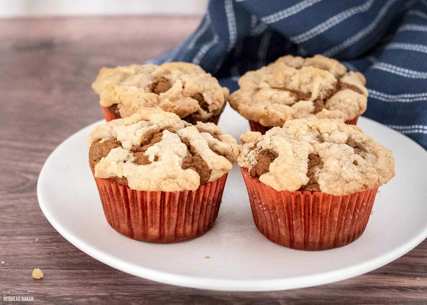 Four pumpkin muffins on a white plate.