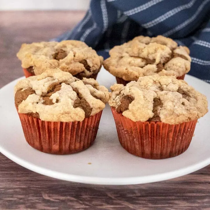 Four pumpkin muffins on a white plate.