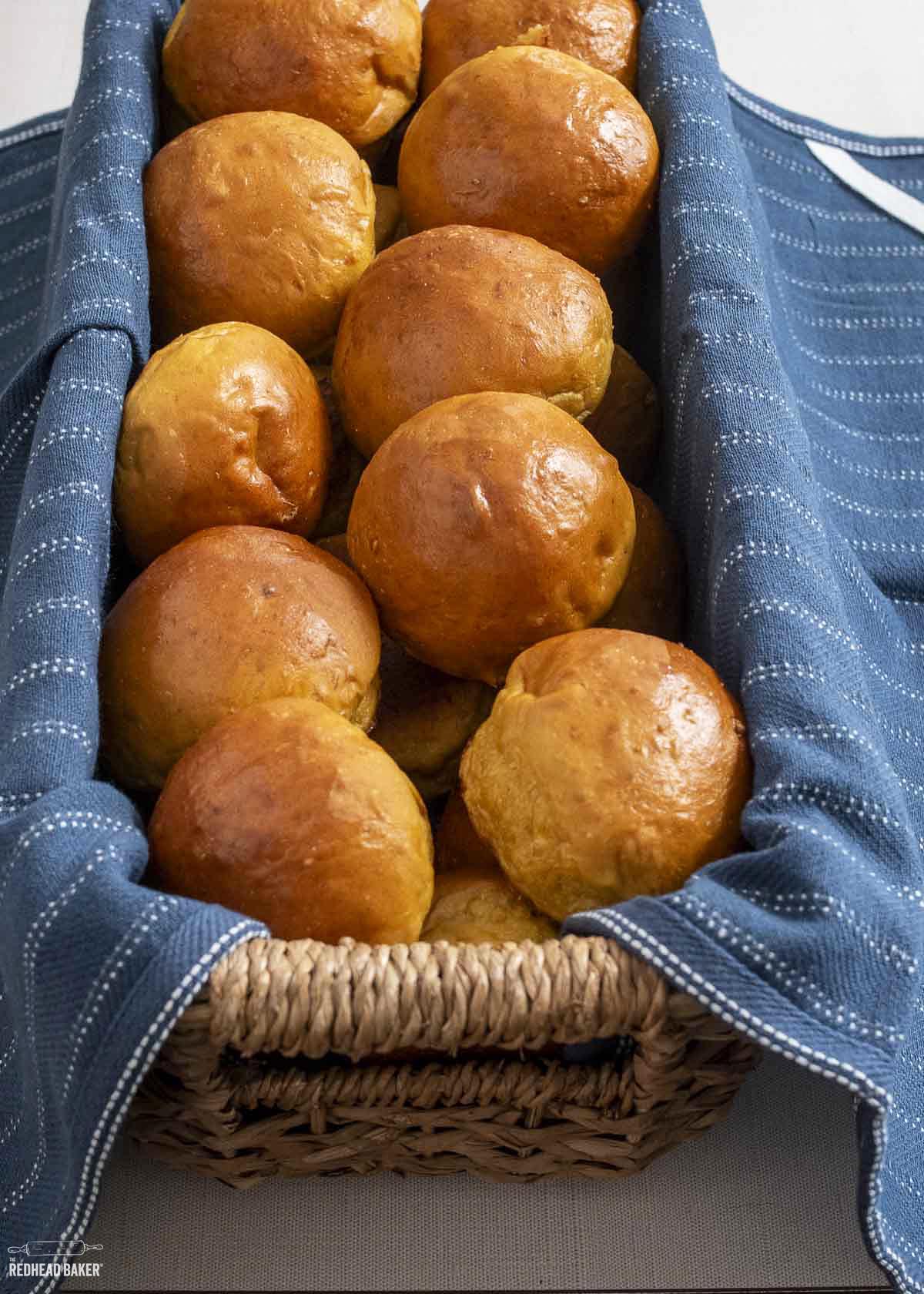 A basket filled with pumpkin brioche rolls.