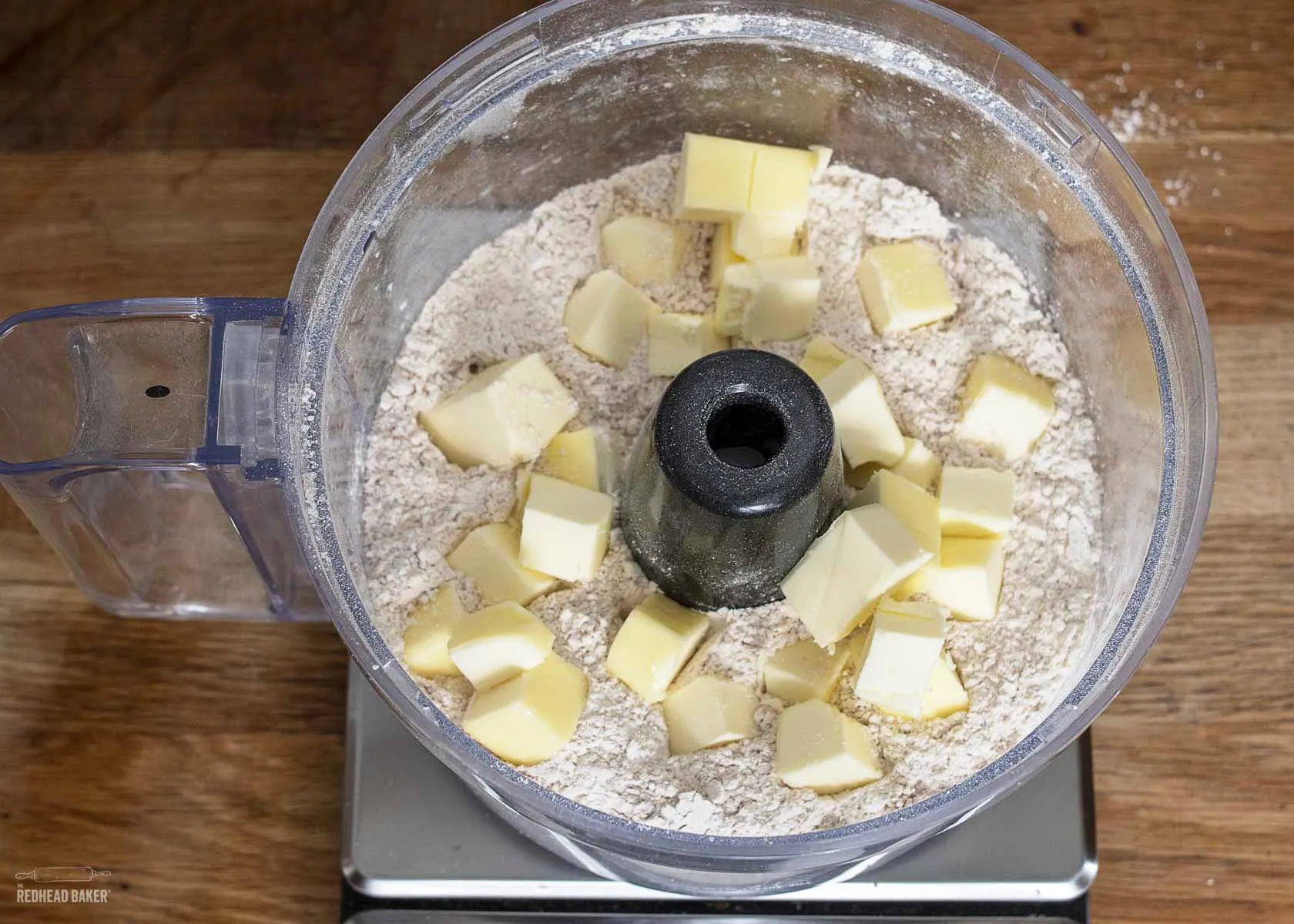 Cubed butter on top of dry ingredients in the food processor bowl.