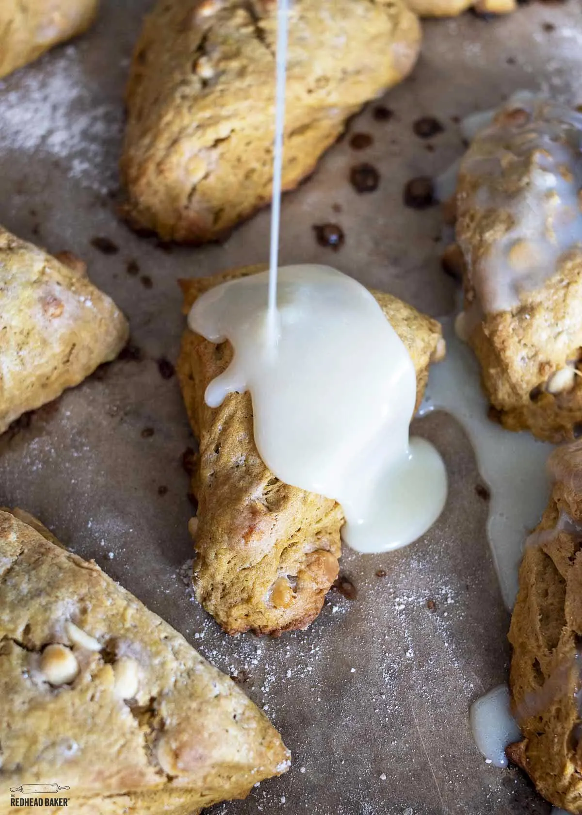 White chocolate ganache being poured onto pumpkin scones.