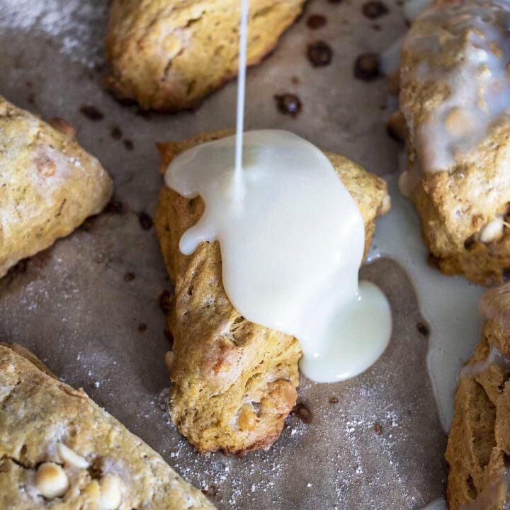 White chocolate glaze being poured onto baked scones.