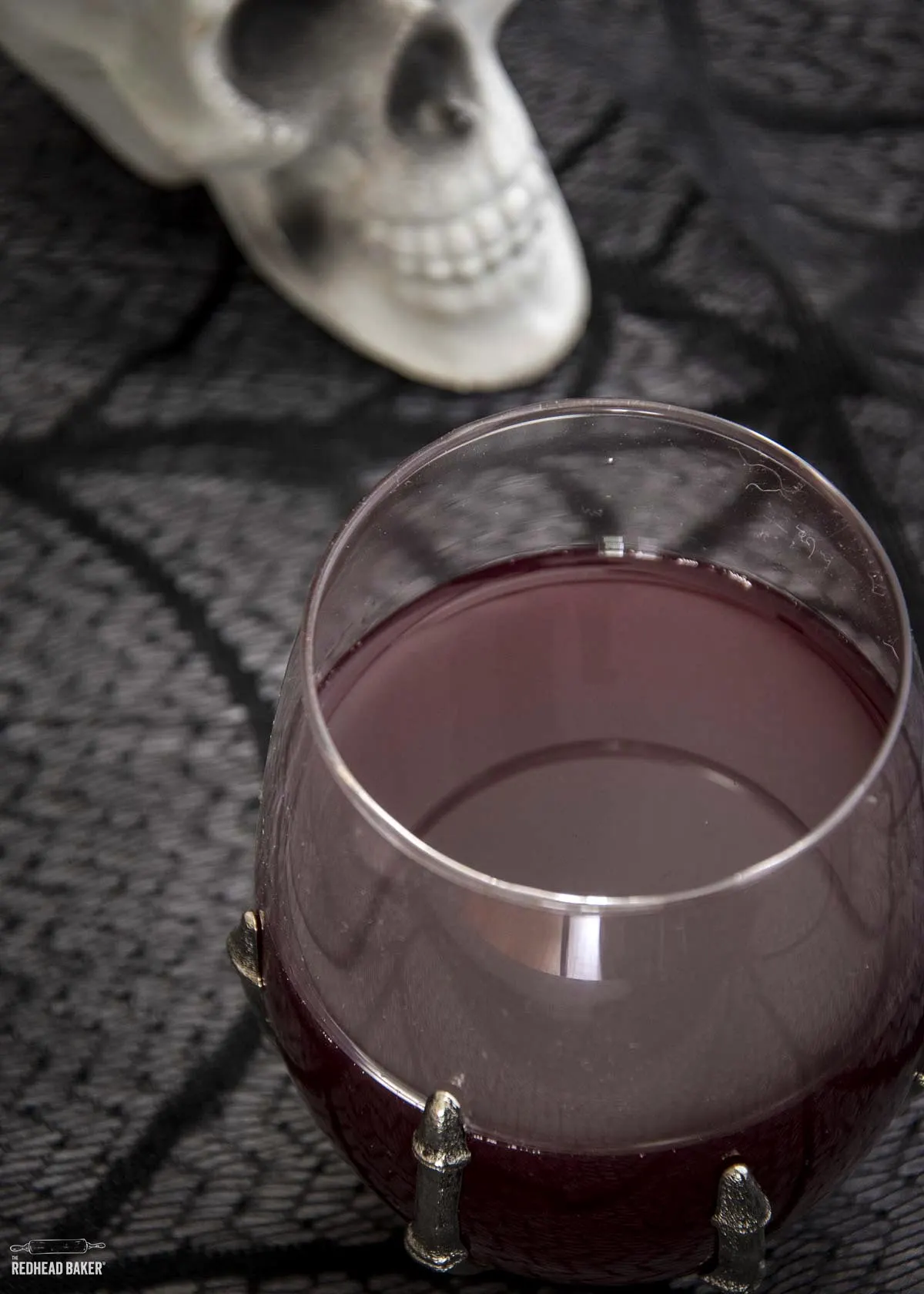 A glass of sangria in front of a plastic skull decoration.