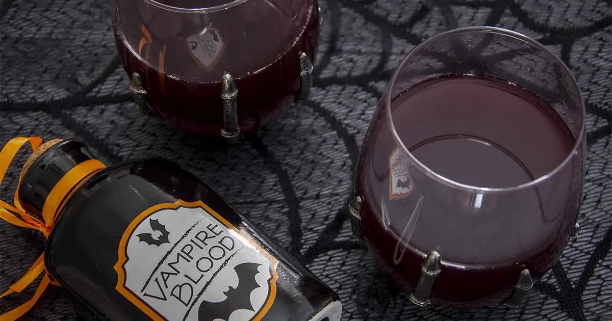 Two glasses of red cider sangria next to a bottle labeled vampire blood.